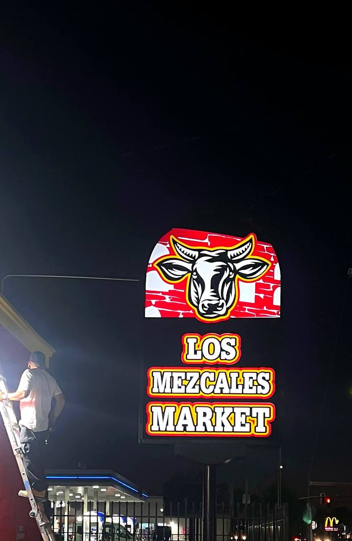 Los Mezcales Market lit cabinet sign at night